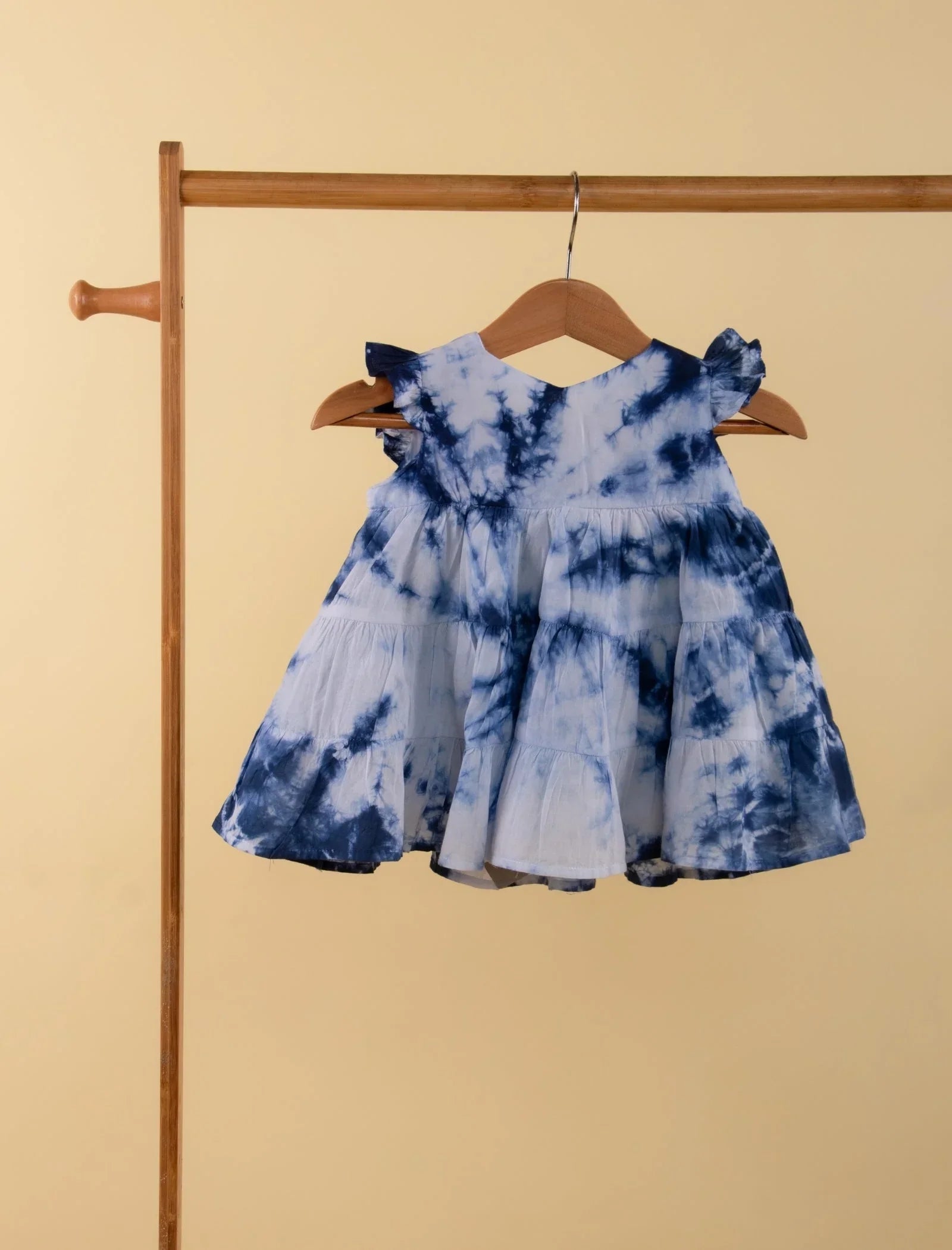 Blue and white tie-dye baby girl dress with ruffle sleeves on wooden hanger