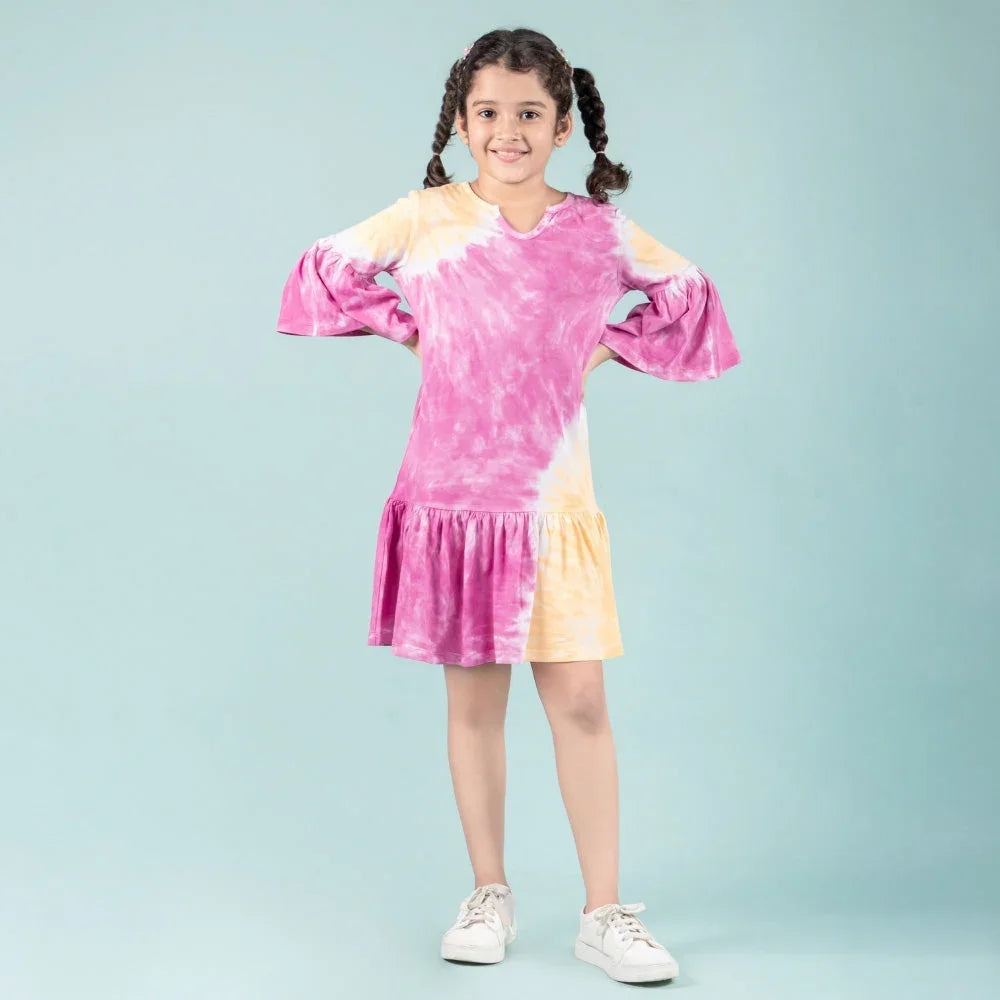 Young girl in a pink and yellow tie-dye dress with ruffled hem and flared sleeves