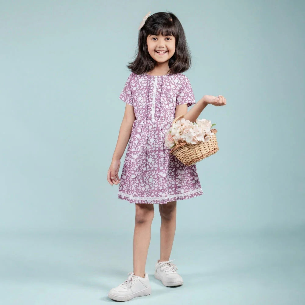 Smiling girl in a short-sleeve floral dress holding a basket of flowers, kids fashion
