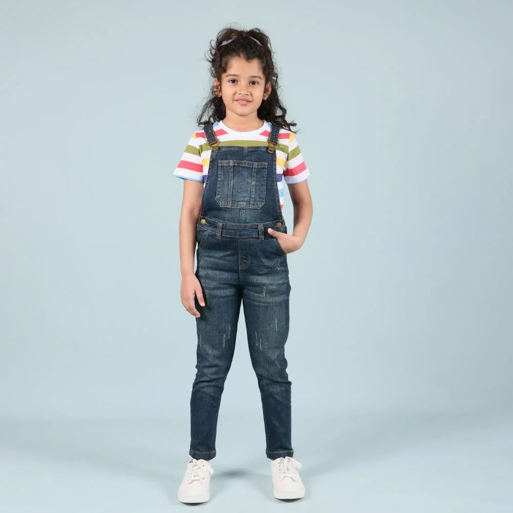 Girl wearing blue denim dungarees and striped t-shirt, kids fashion photoshoot