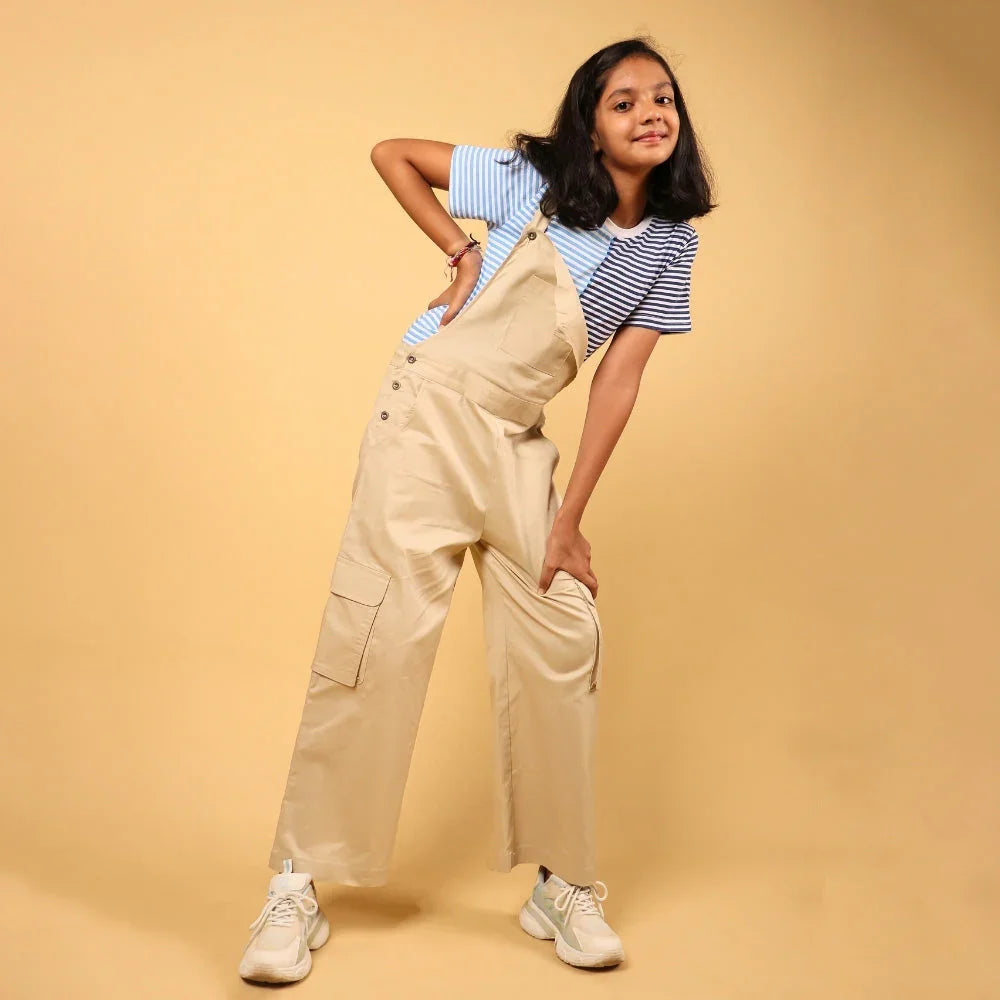 Girl wearing beige dungarees and striped t-shirt, casual kids fashion for 8-year-olds