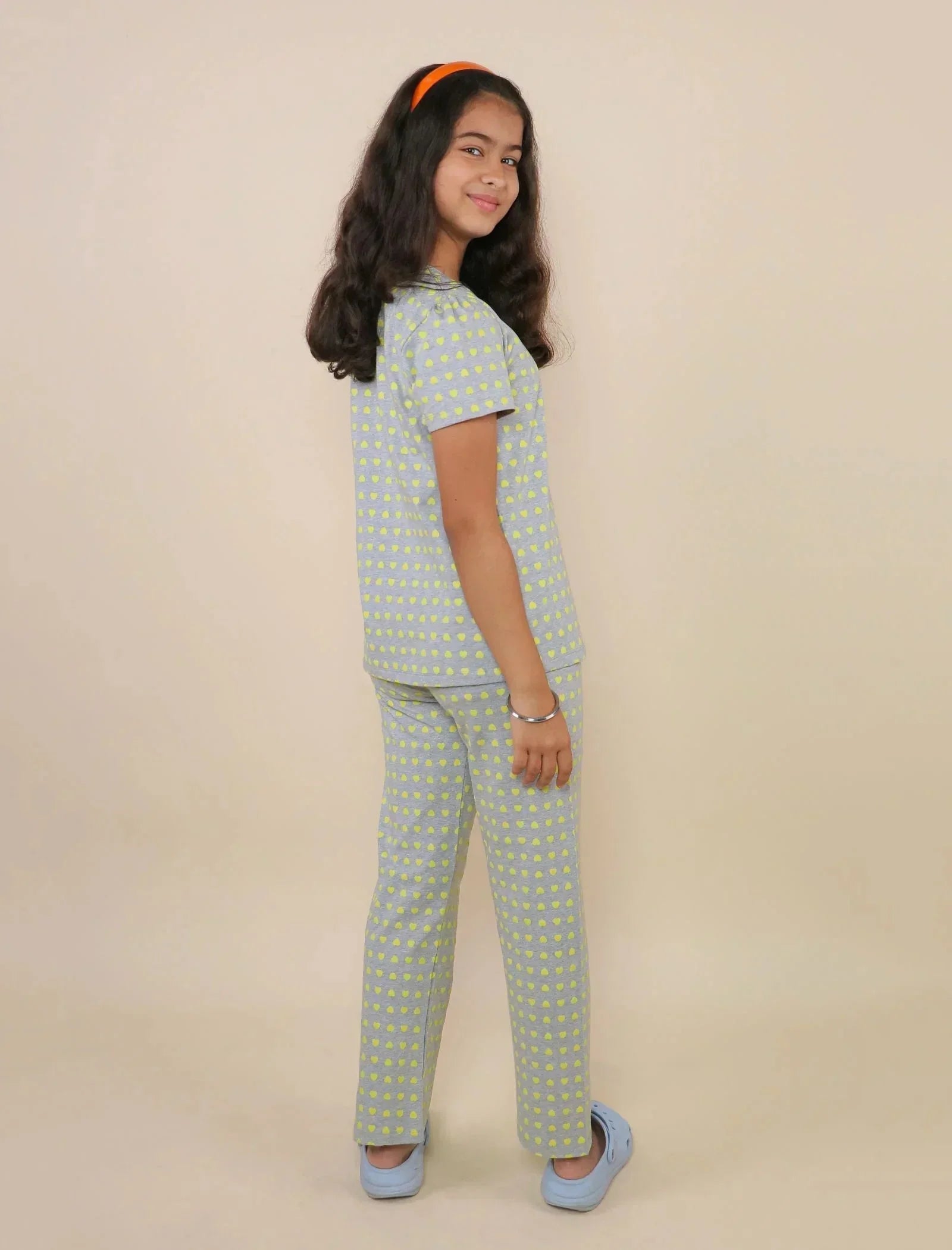 Girl wearing a grey cotton night suit with yellow heart print, posing in studio.