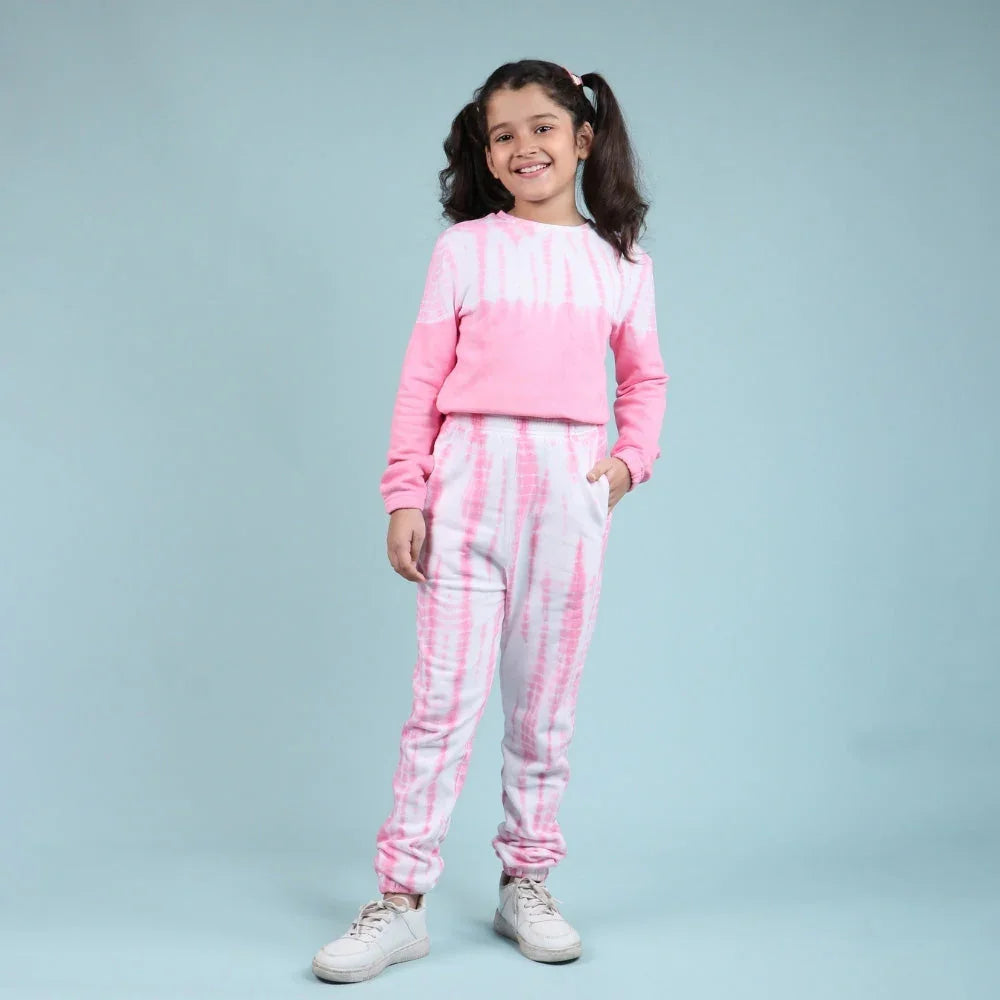 Girl wearing pink and white tie-dye jogger set for kids, standing against a light blue background.