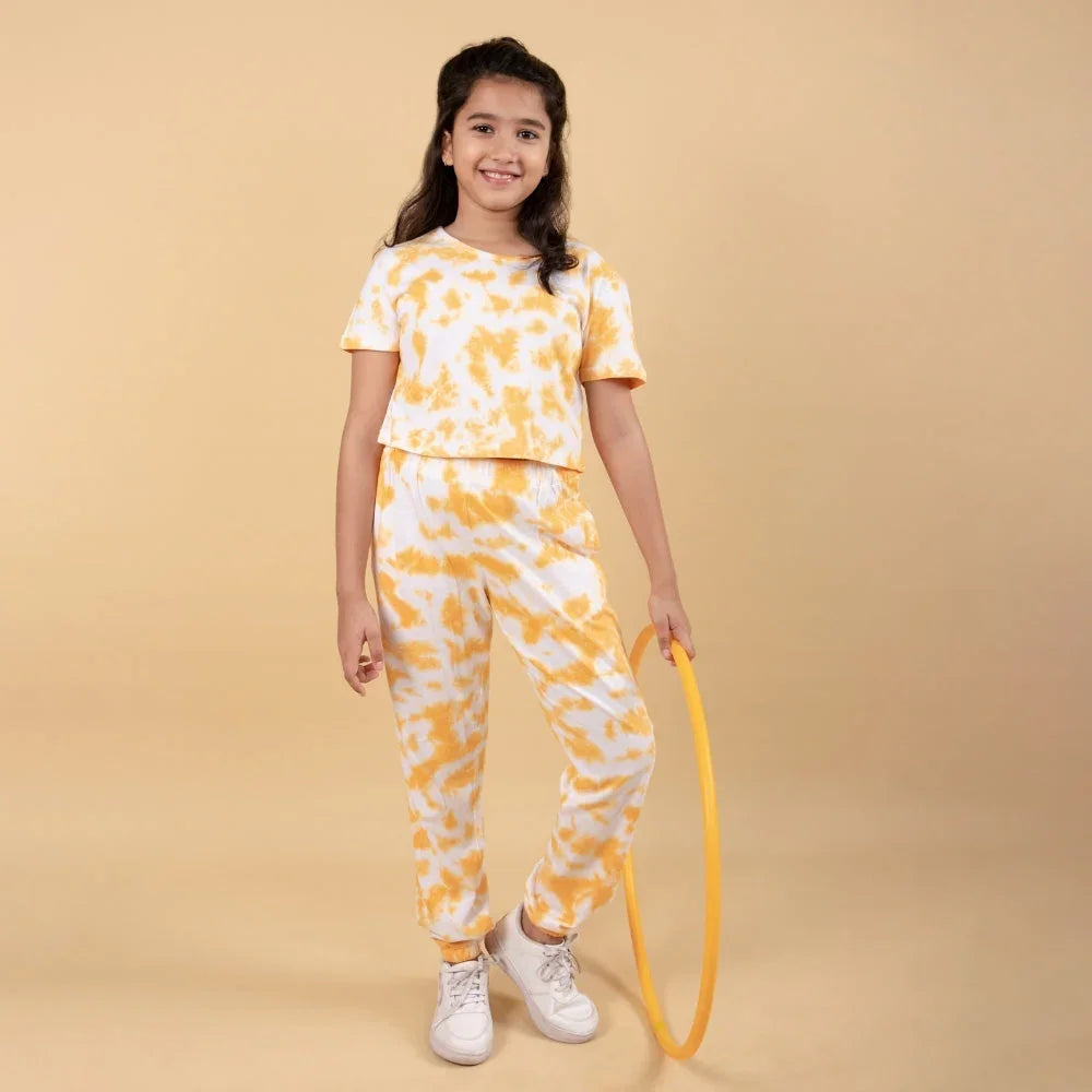 Girl in yellow and white tie-dye jogger set holding hula hoop, casual kids fashion outfit