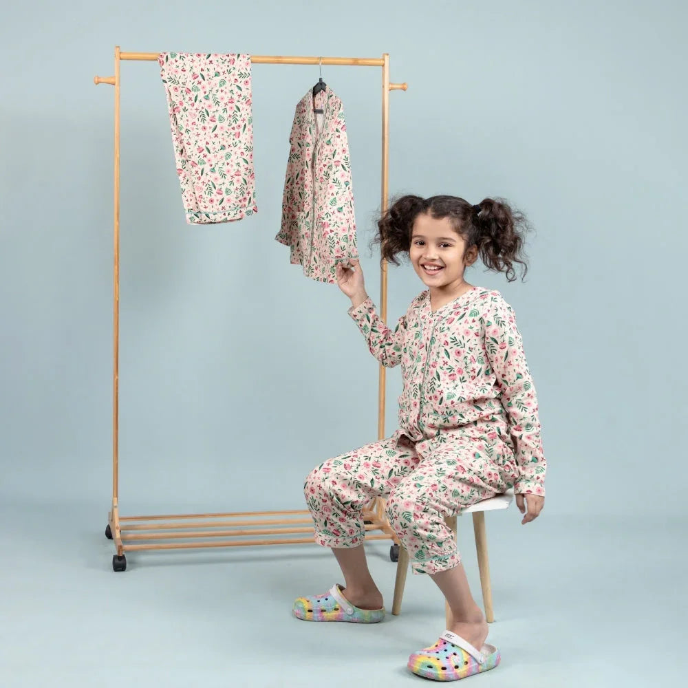 Girl wearing floral printed night suit for girls, sitting and smiling in a studio setting