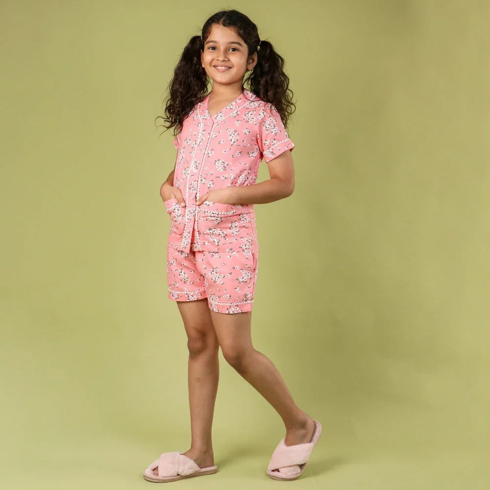 Girl wearing pink floral night suit shorts set for kids, smiling, with pink slippers