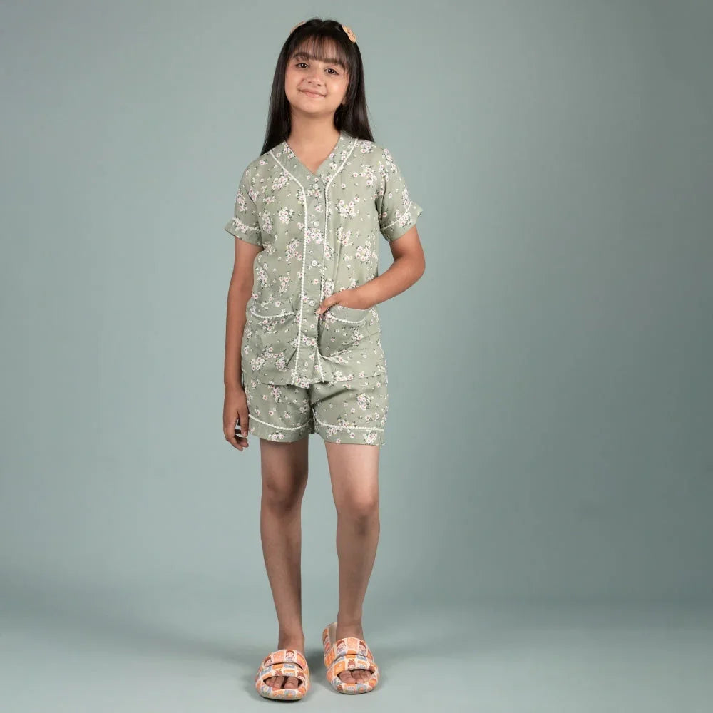 Girl wearing green floral short-sleeve night suit set, standing against light background