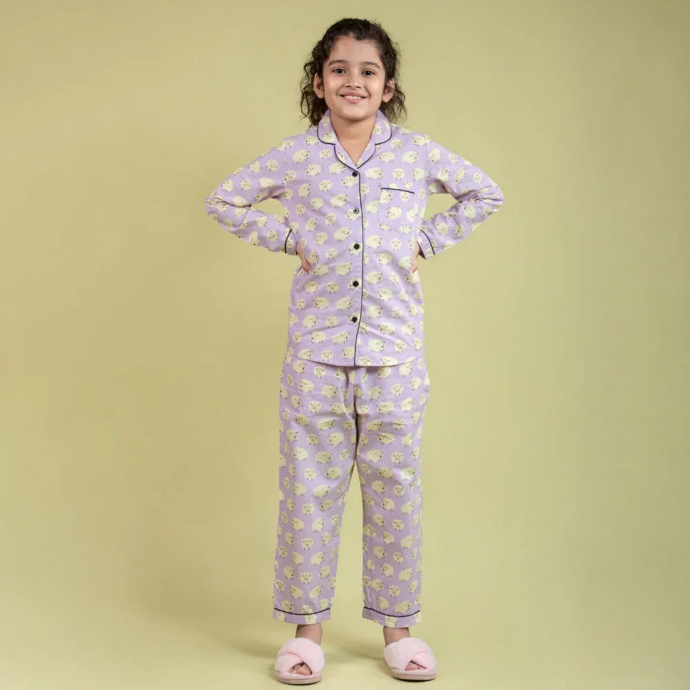Girl wearing lavender printed night suit set with slippers, hands on hips, smiling