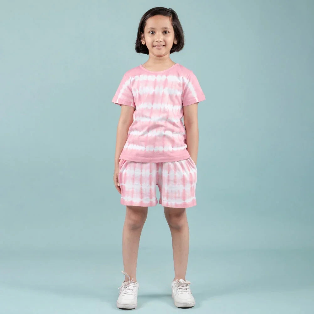 Girl wearing pink and white tie-dye nightdress set with shorts, standing against blue background