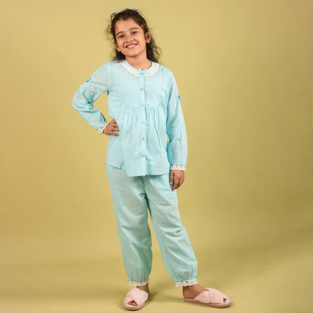 Girl wearing light blue cotton nightdress set with lace trim, posing in studio