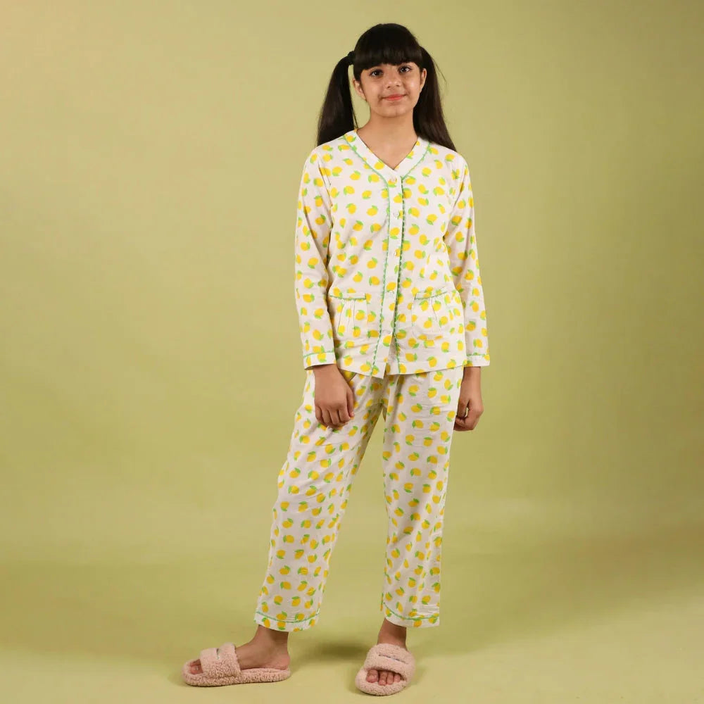 Girl in yellow printed nightdress pajamas set, long sleeves, pink slippers, studio background