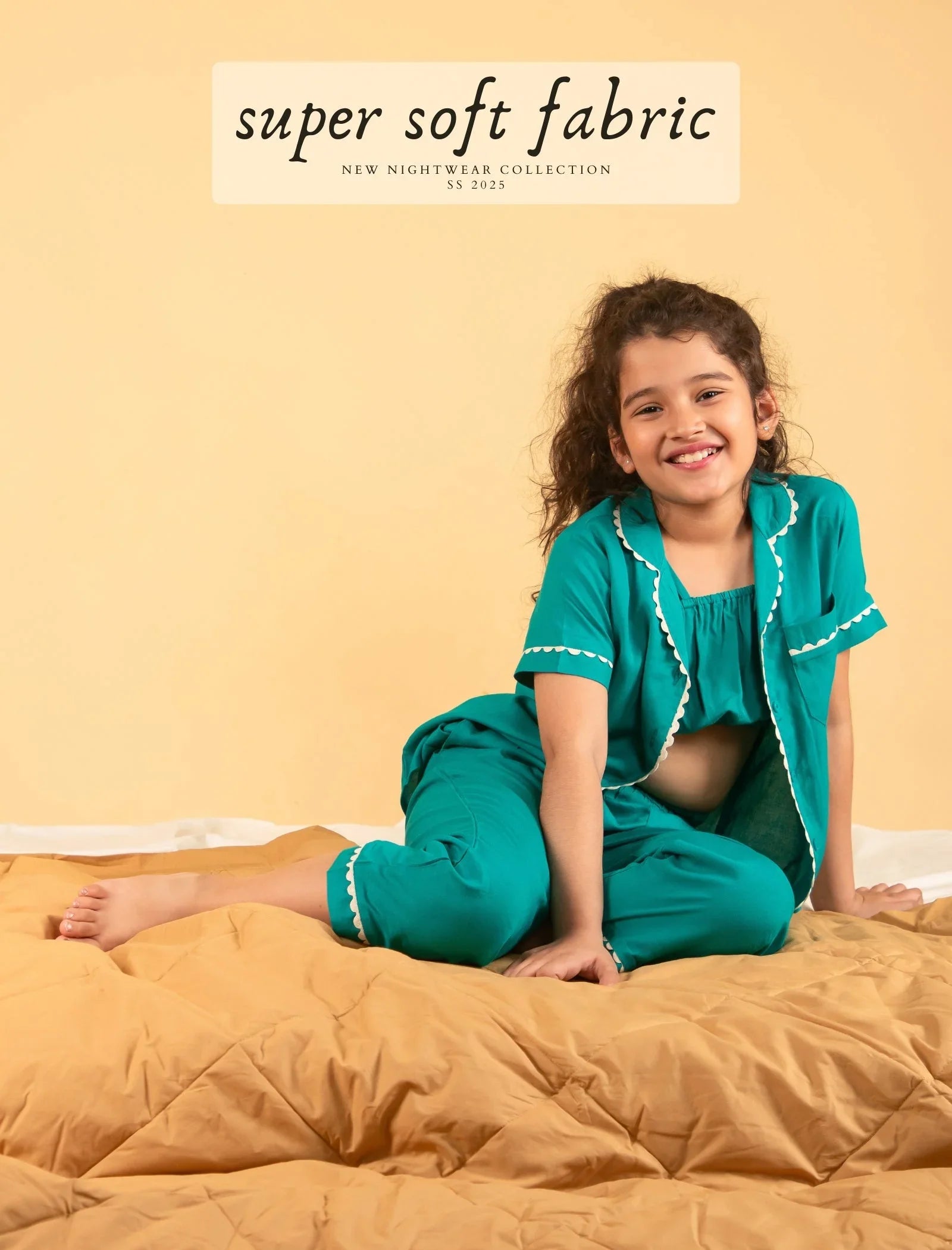 Smiling girl in teal nightdress set sitting on bed, comfy kids nightwear, super soft fabric.