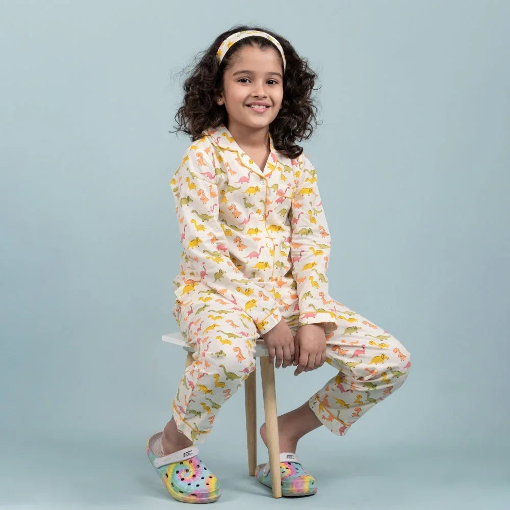 Smiling girl in colorful printed kids night suit and headband, sitting on a stool