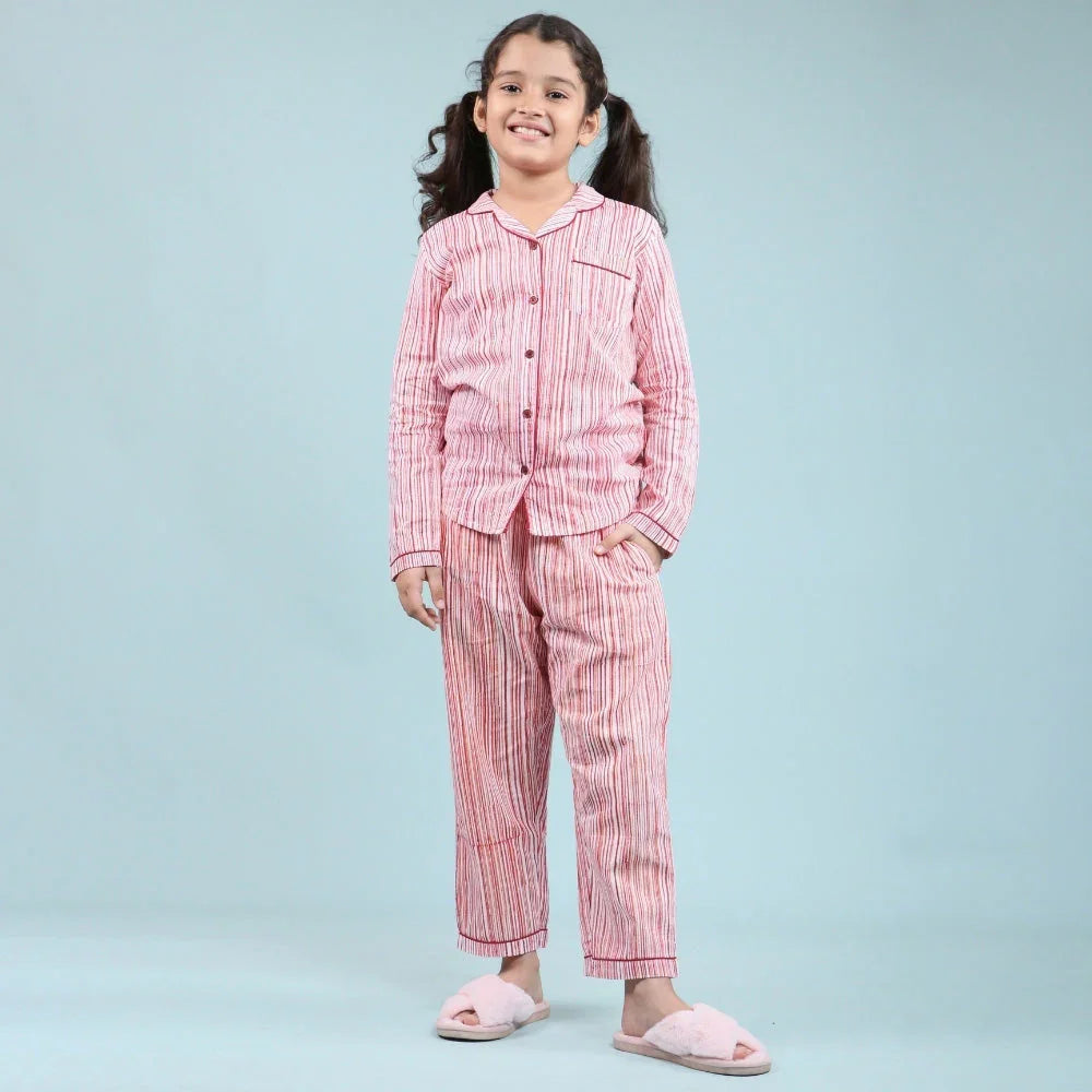 Girl in striped pink nightwear pajama set and slippers on light blue background
