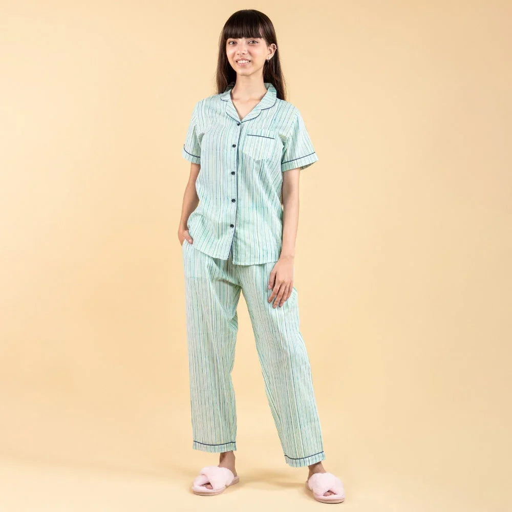 Girl in light green striped nightwear set with short-sleeve shirt and pants, beige background