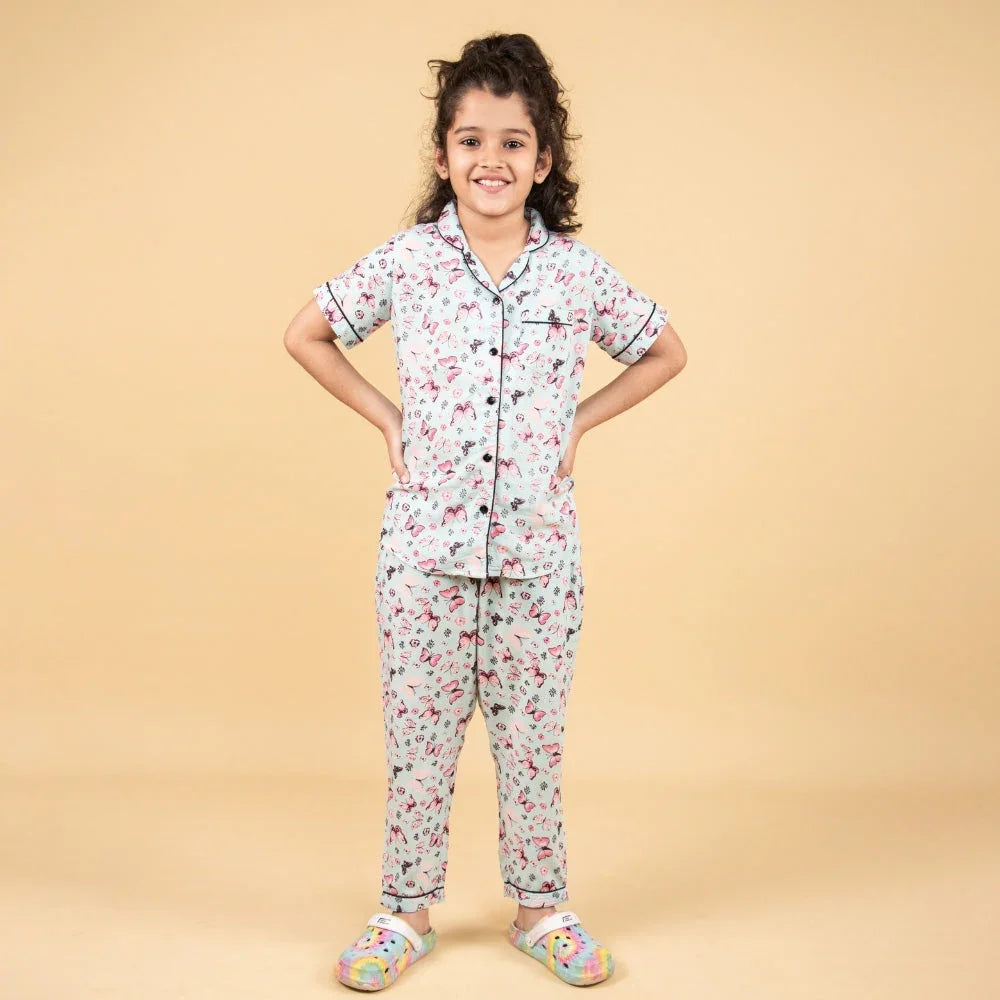 Smiling girl wearing printed nightwear pajama set for girls, standing on beige background