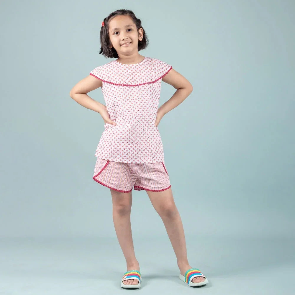 Girl wearing pink printed night suit set with shorts, posing against a plain background