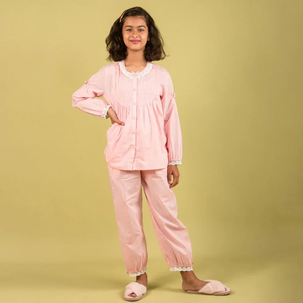 Girl in pink cotton nightwear set with lace trim, standing against yellow background