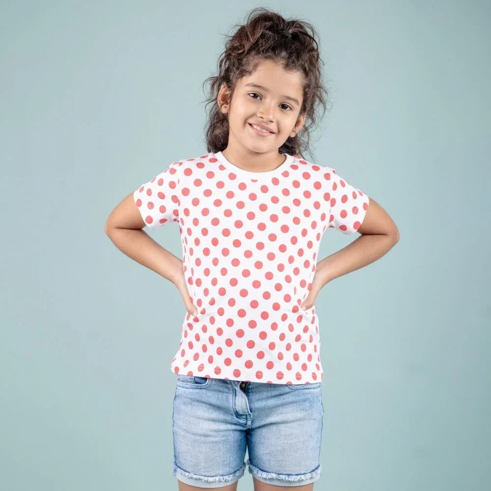 Smiling girl in white and red polka dot t-shirt and denim shorts, kids fashion outfit