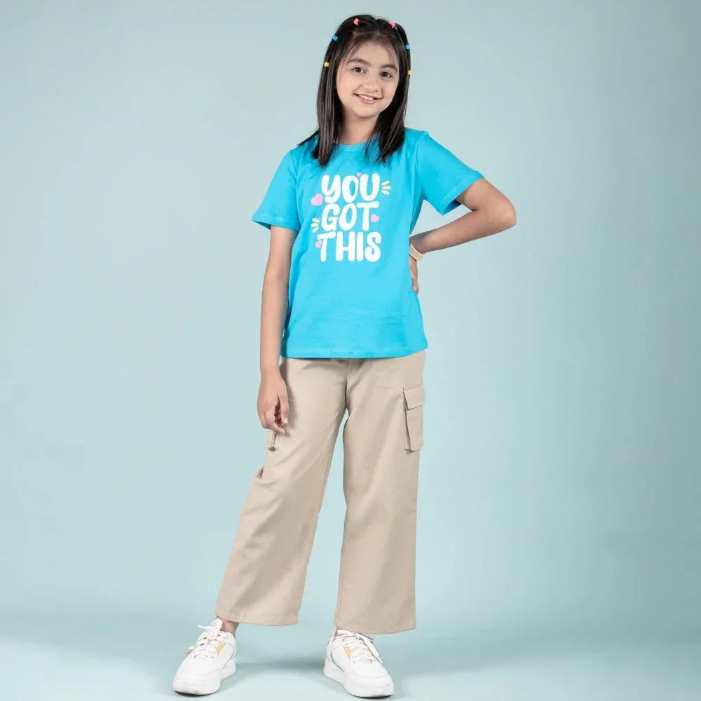 Girl wearing a blue graphic T-shirt with 'You Got This' and beige cargo pants, casual kidswear