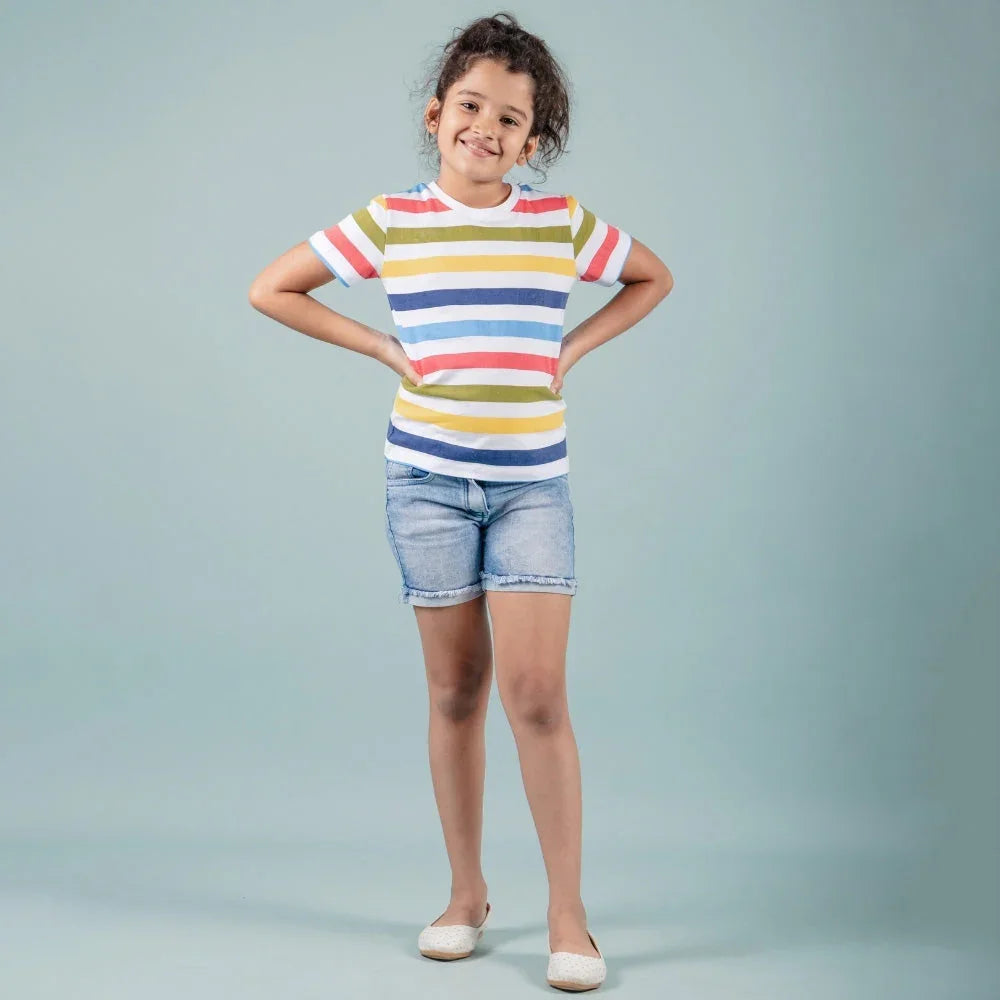 Smiling girl wearing striped t-shirt and denim shorts, casual kids fashion outfit