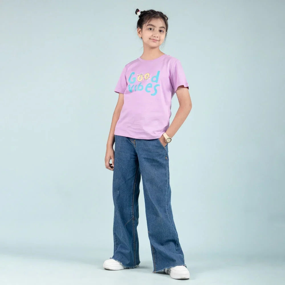 Young girl in a lavender Good Vibes t-shirt and wide leg blue jeans, kids fashion outfit