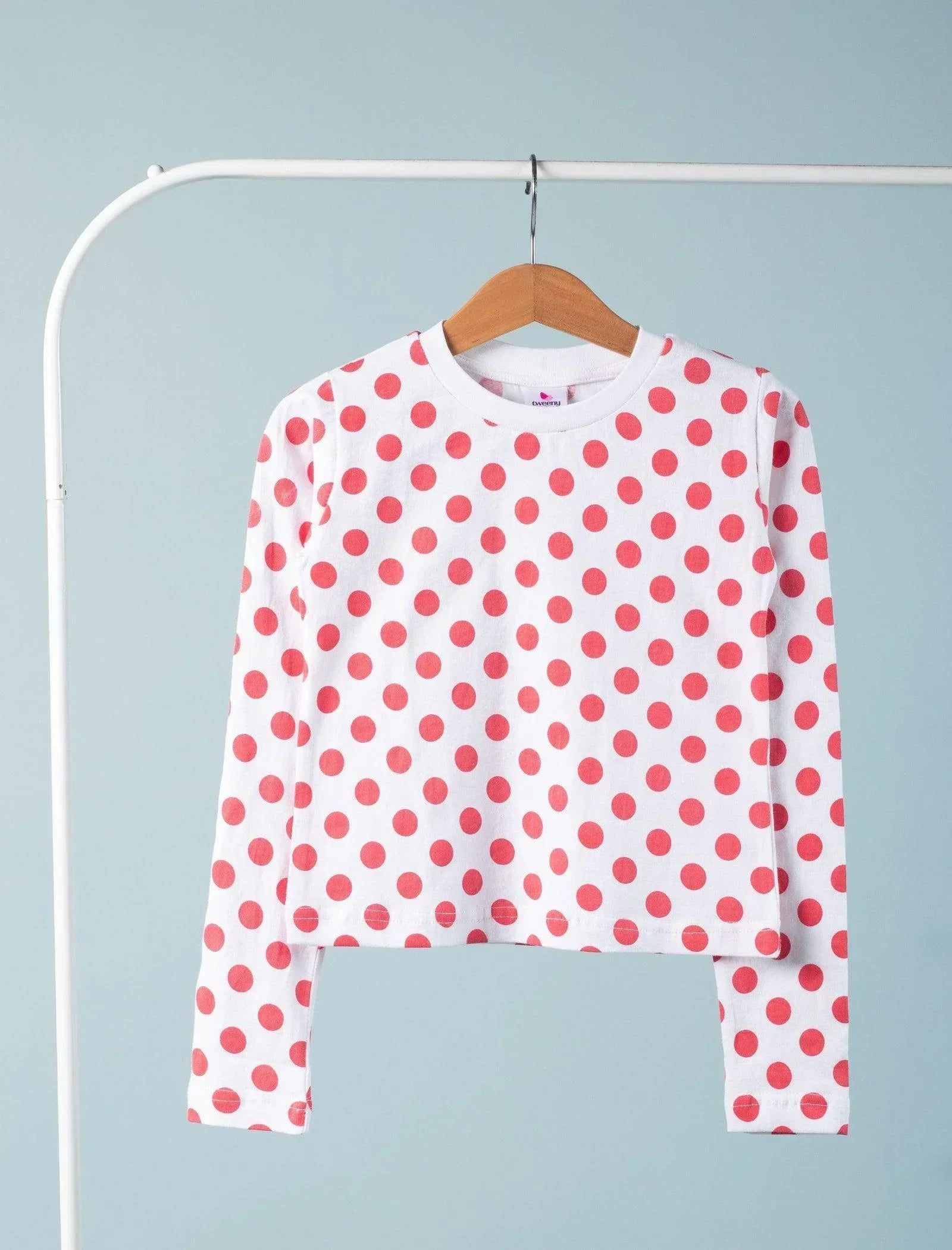 White girls long sleeve top with red polka dots, hanging on wooden hanger