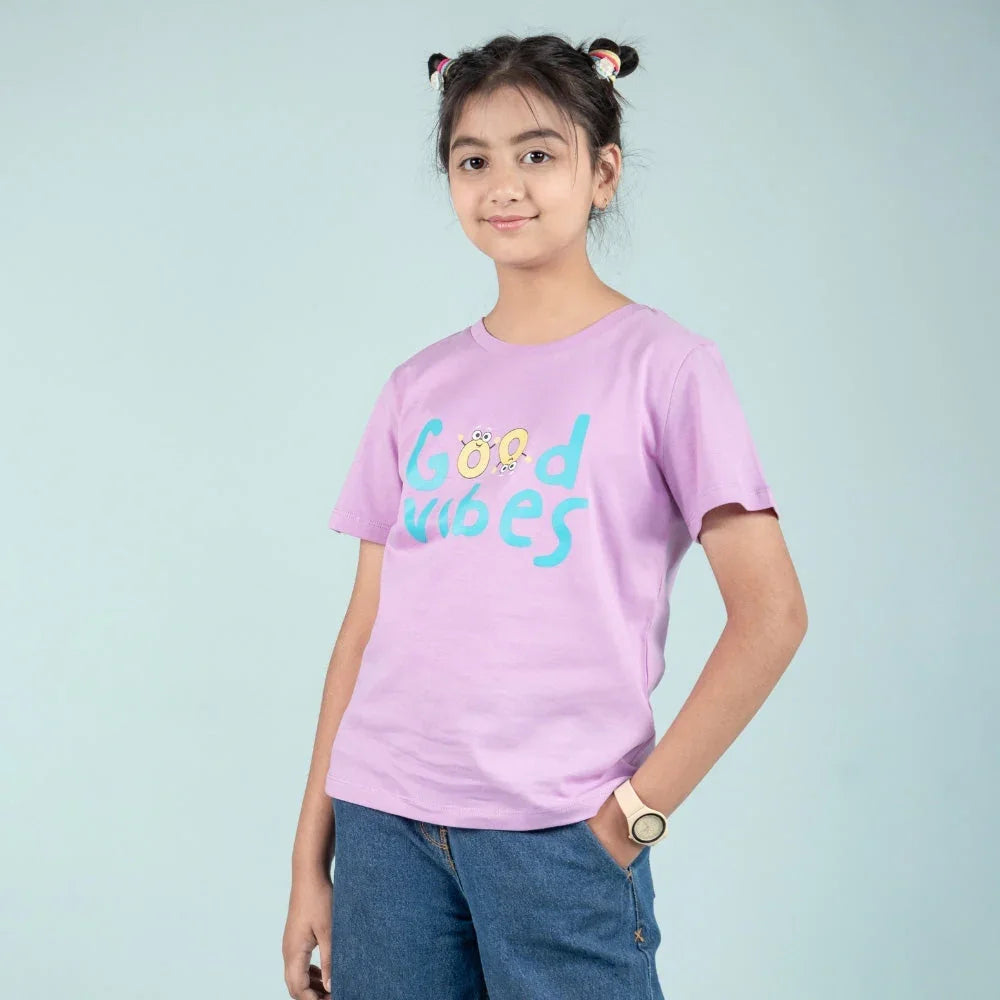 Preteen girl in a lavender Good Vibes t-shirt and blue jeans, casual kids fashion outfit