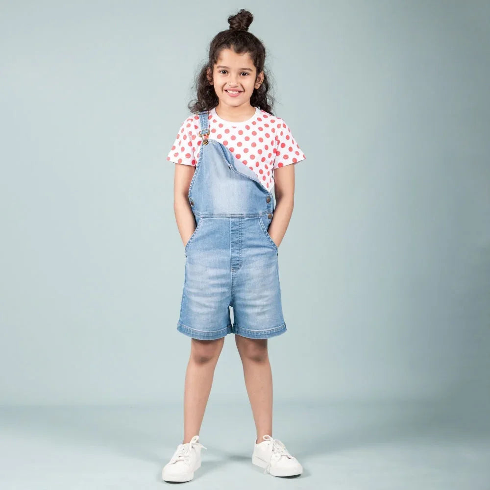Smiling girl wearing denim dungaree shorts and a red polka dot t-shirt, kids fashion