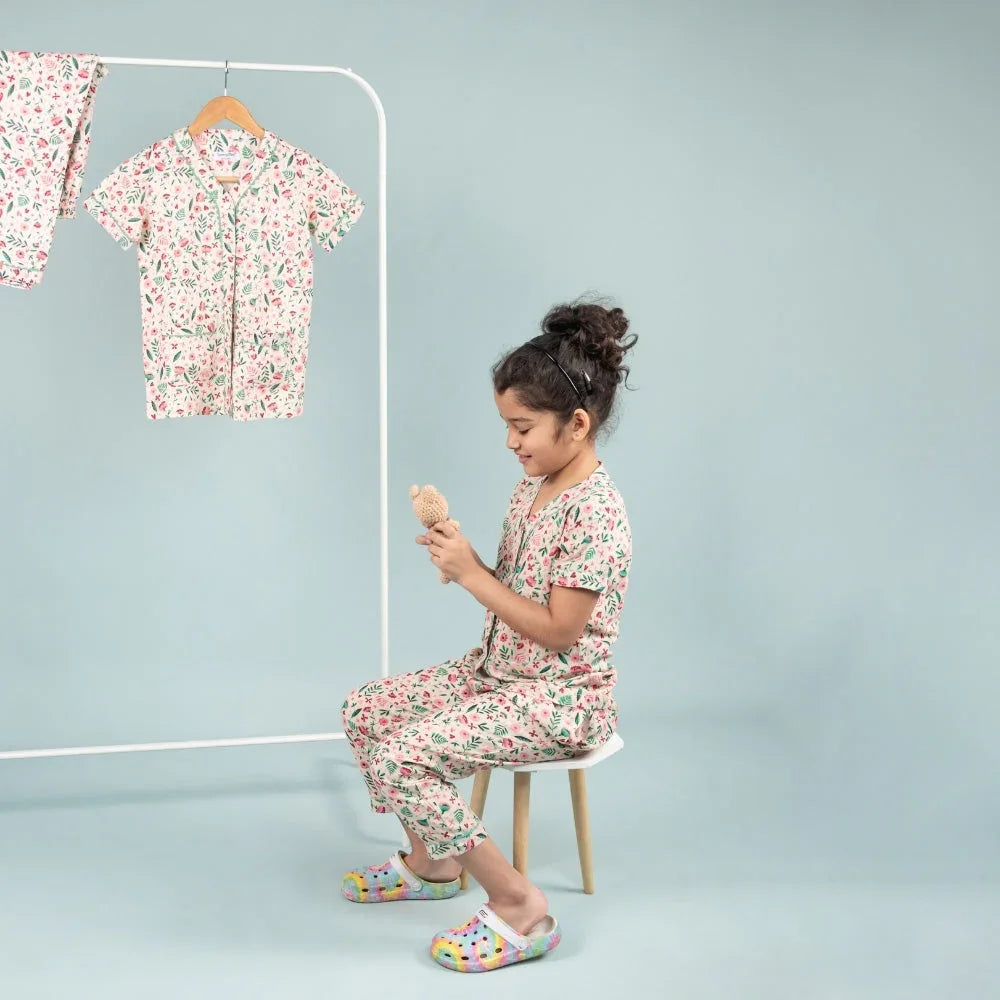 Girl wearing floral print night suit set, sitting on stool and holding a toy, kids sleepwear