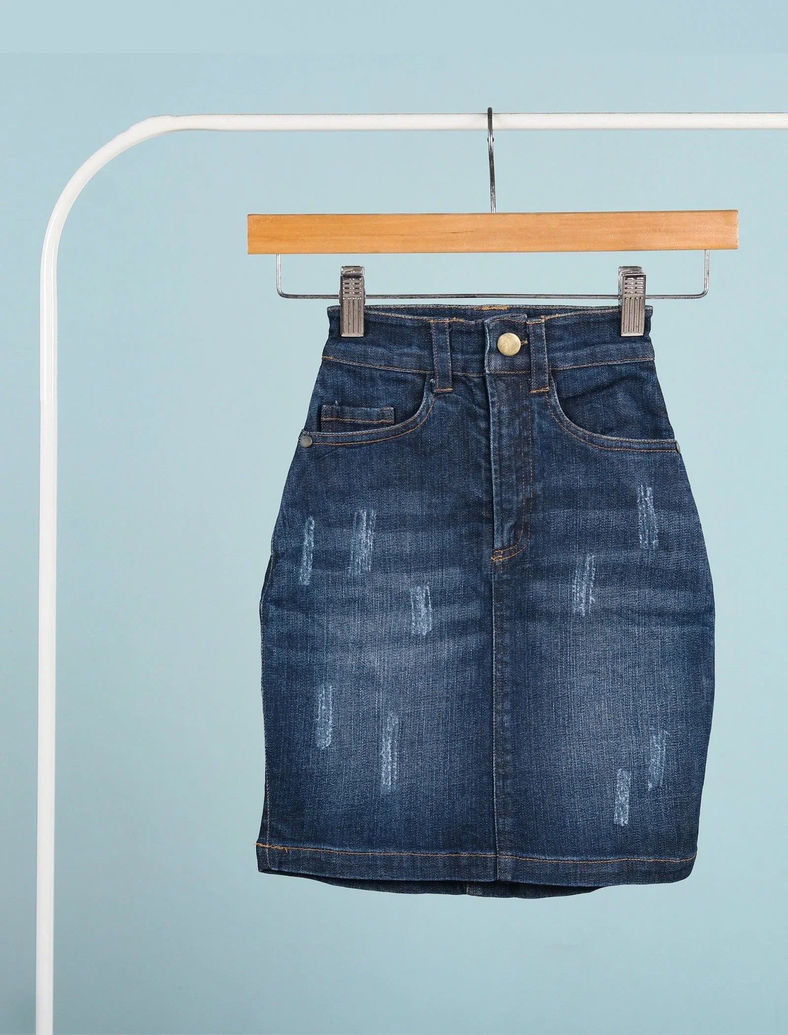 Blue denim skirt for girls age 7, high-waisted with distressed details, hanging on hanger